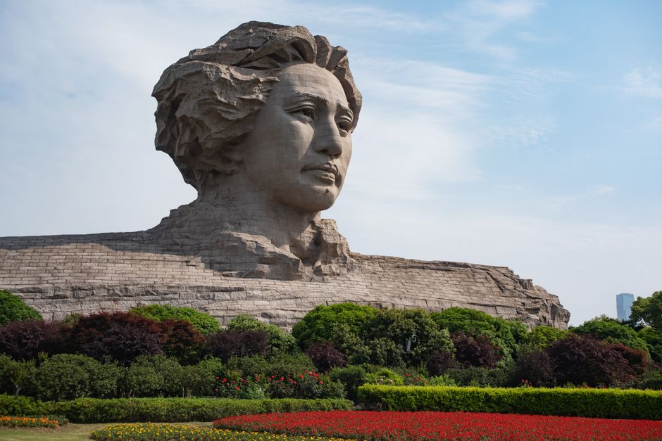 Large stone statue of a prominent figure set amidst a lush park landscape.