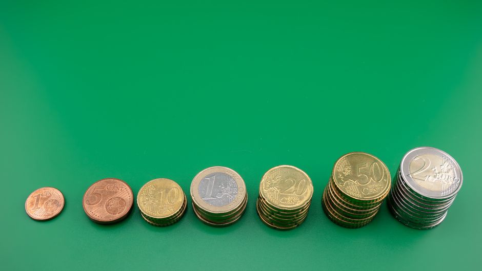 Various euro coins stacked incrementally on a vibrant green background.