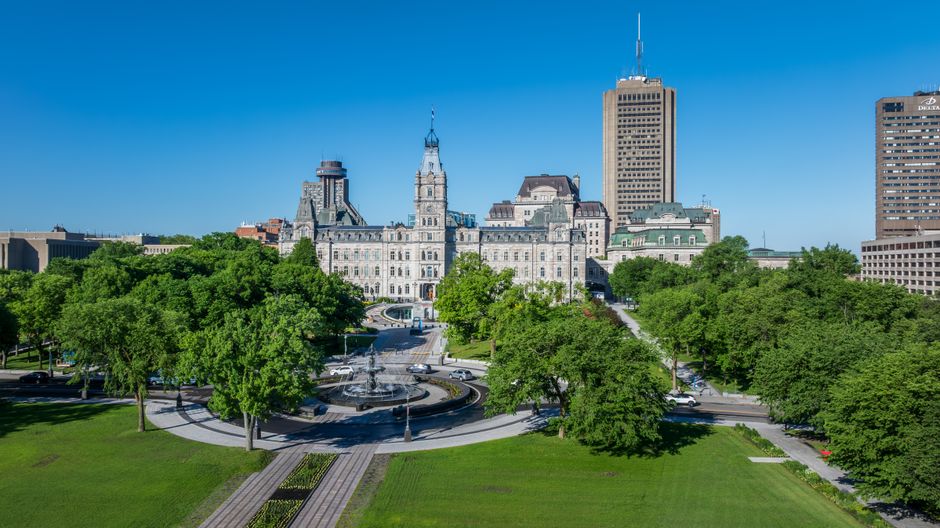 Stunning aerial view of Quebec's Parliament Building surrounded by lush greenery on a sunny summer day.