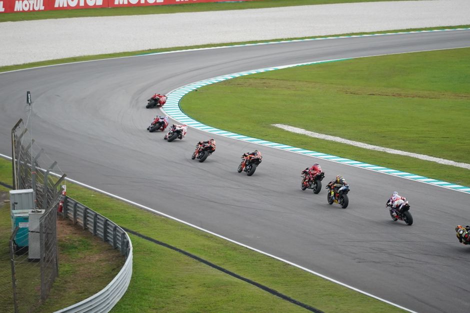 Motorcycles speed around a track curve, showcasing thrilling motorsport action.