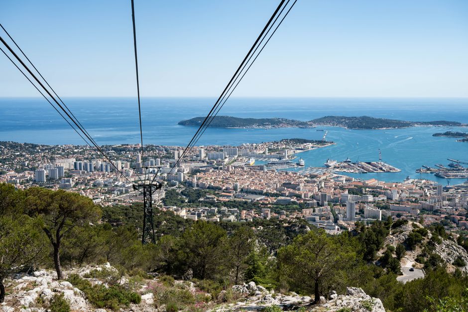 A stunning aerial view of Toulon city and the Mediterranean Sea from a hillside cable car perspective.