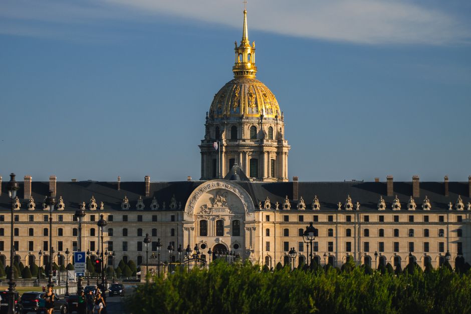 The majestic dome of Les Invalides in Paris, France, illuminated by daylight against a blue sky.