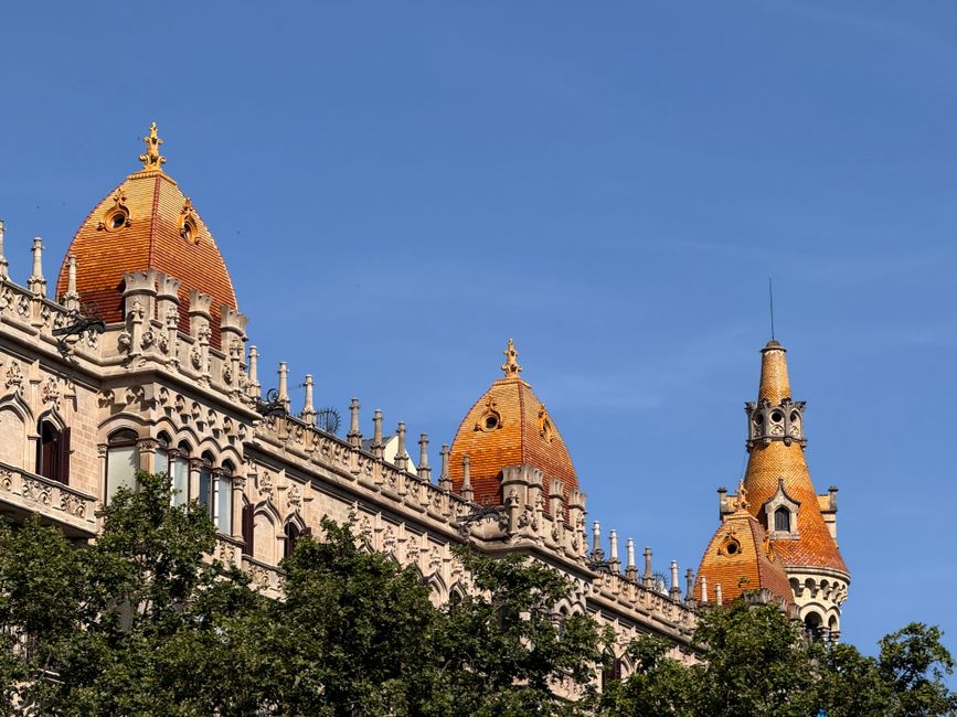 Architectural detail of Casa de les Punxes in Barcelona with vibrant orange spires against blue sky.