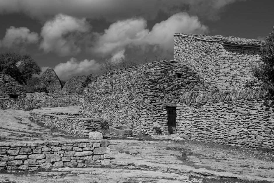 Black and white image of traditional stone huts in Gordes, a historic village in France.