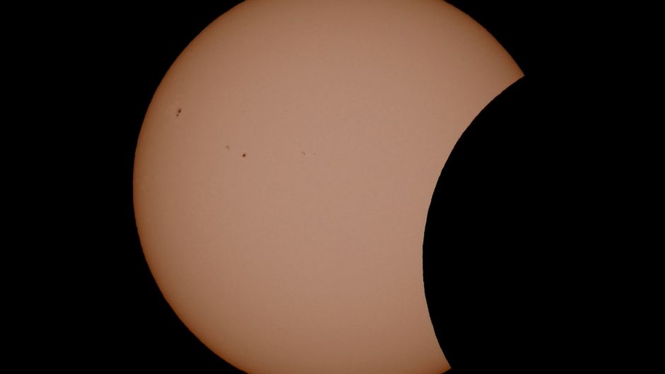 Stunning view of a partial solar eclipse with visible sunspots captured in daytime.