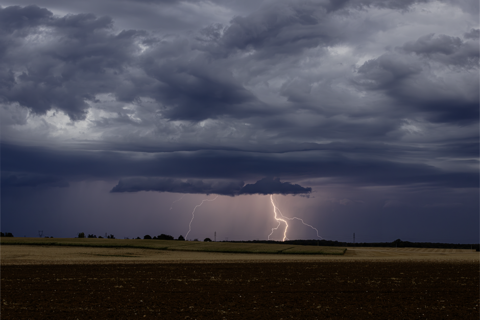 Lightning illuminates a dark stormy sky over a rural landscape in France.