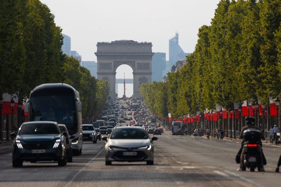 Busy Champs-Élysées street view with Arc de Triomphe in the background, Paris, France.