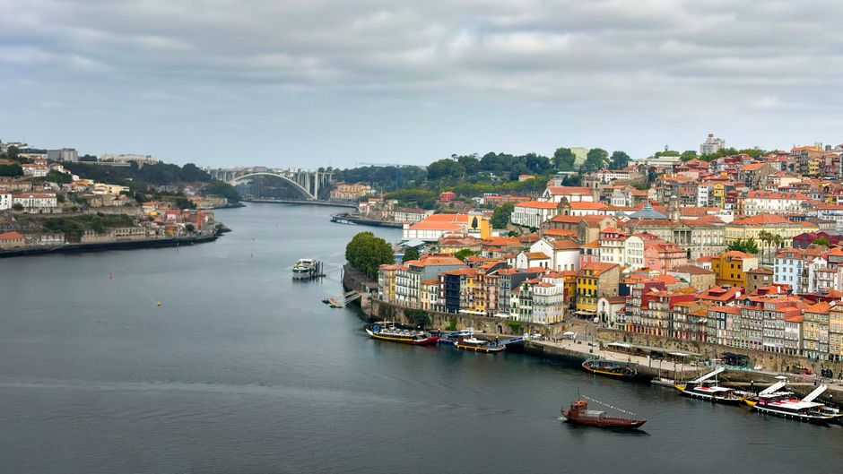 Panoramic view of Porto's colorful riverside buildings and Arrábida Bridge spanning the Douro River.