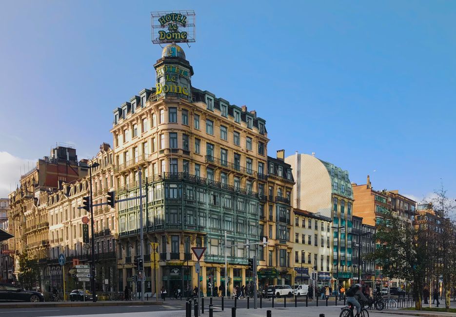 Historic Hotel Le Dome building on bustling Brussels street, sunny day scene in Belgium.