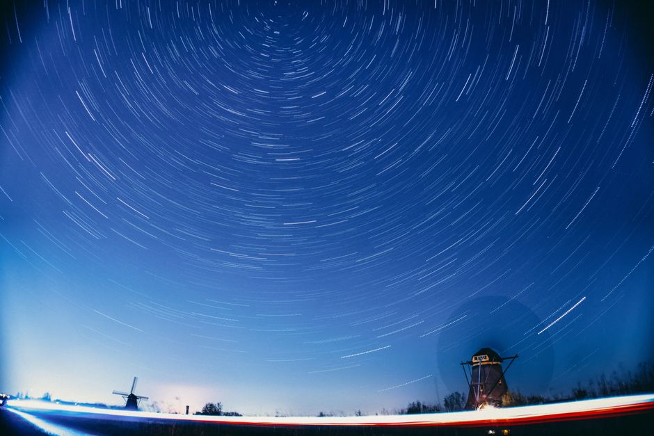 A mesmerizing view of star trails over iconic Dutch windmills in Kinderdijk, Netherlands.