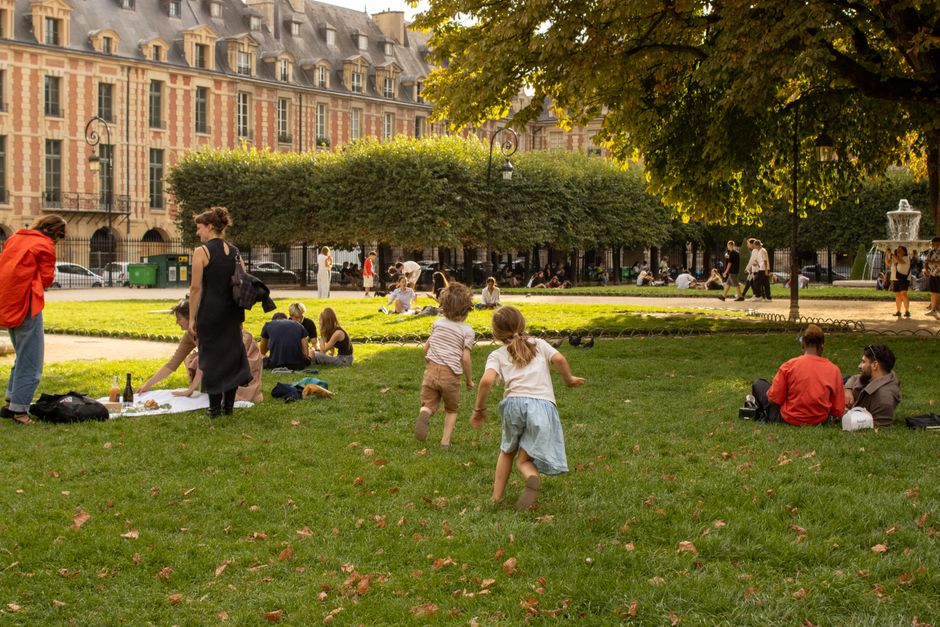 People enjoying leisure at Place des Vosges in Paris, surrounded by historic architecture and lush greenery.