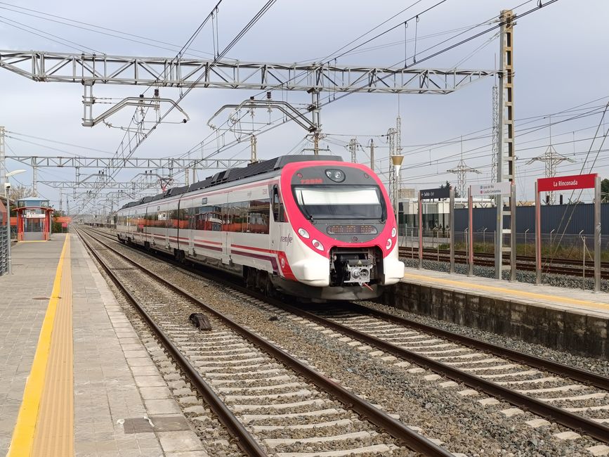 A modern train arrives at La Rinconada station in Andalucía, Spain on a clear day.