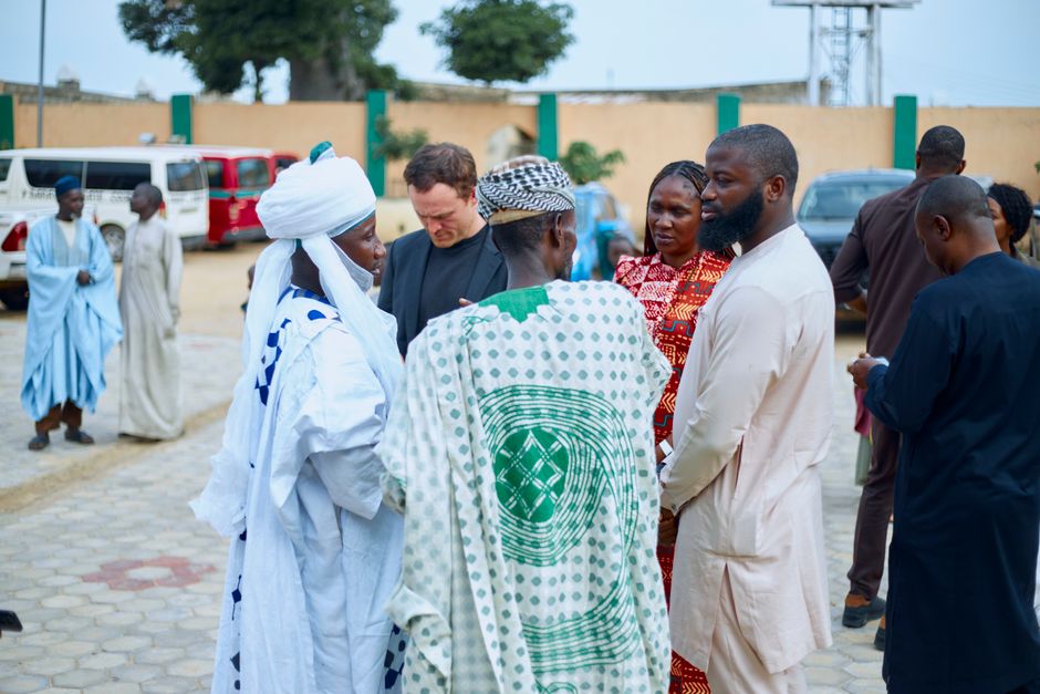 A group of people in traditional and modern attire gather outdoors, showcasing cultural diversity and interaction.
