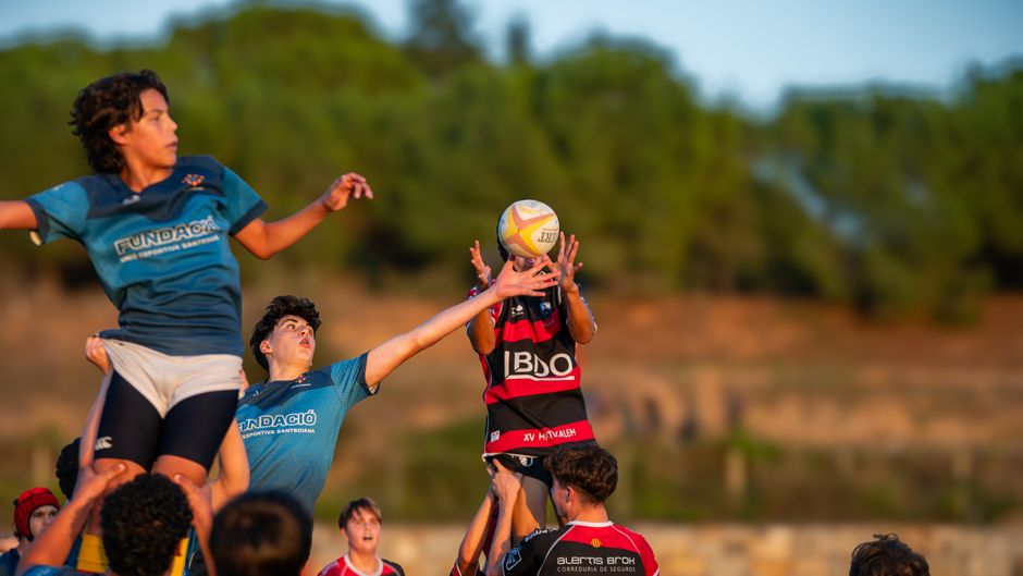 Dynamic action shot capturing young rugby players leaping for the ball during a match.