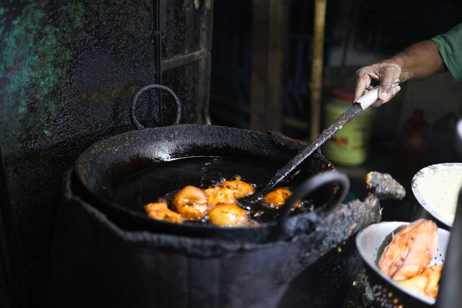 A street vendor frying snacks in a large pan, showcasing traditional culinary methods.