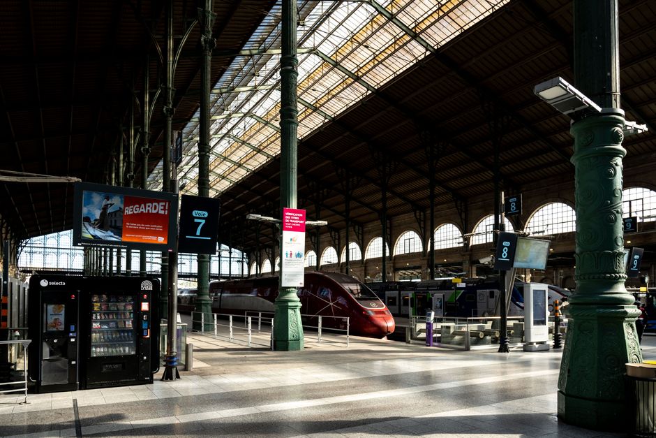 Interior view of Gare du Nord train station in Paris, showcasing a red high-speed train.