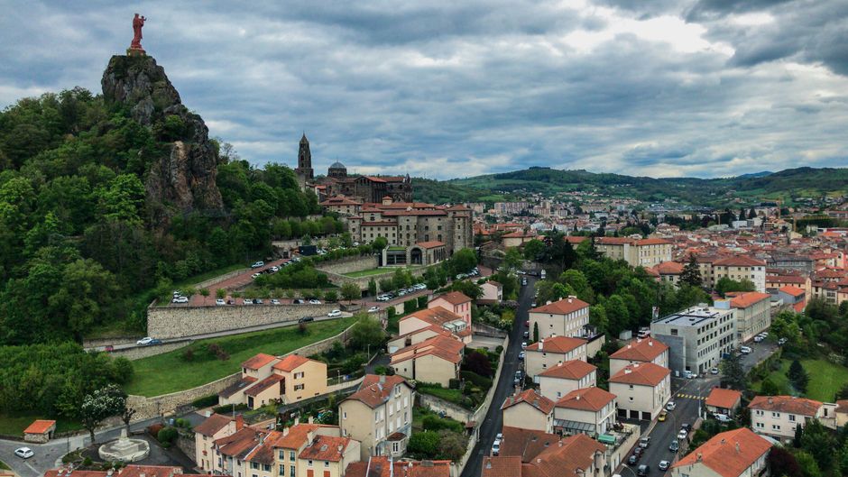 Aerial view of Puy-en-Velay, France with the notable Statue of Mary and picturesque townscape.