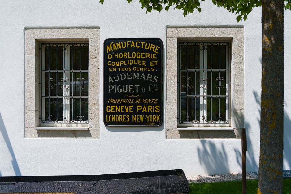 Vintage Audemars Piguet sign on a building wall in Switzerland, showcasing horological heritage.
