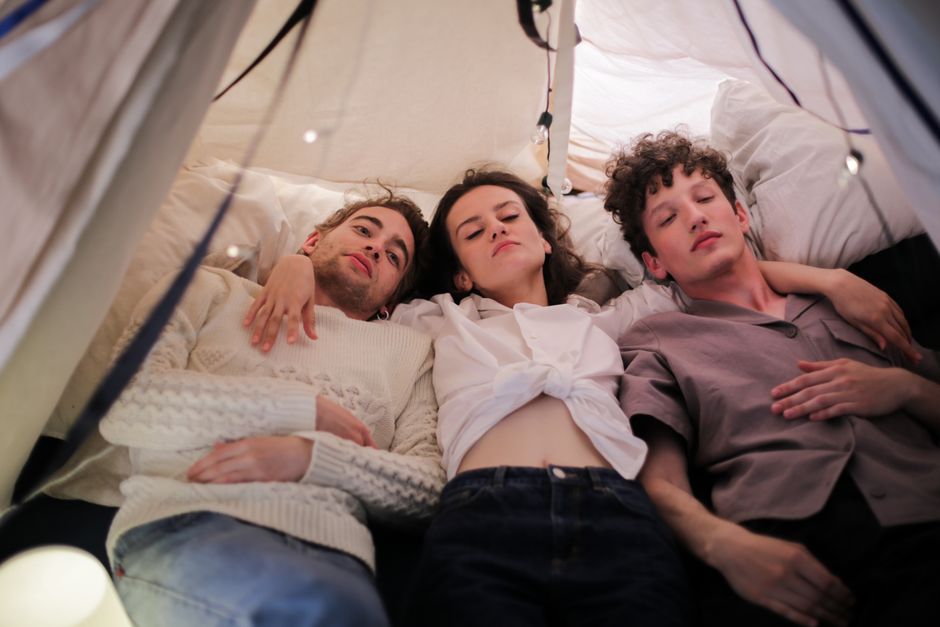 Three adults relaxing together in a cozy indoor tent, enjoying a moment of togetherness and comfort.