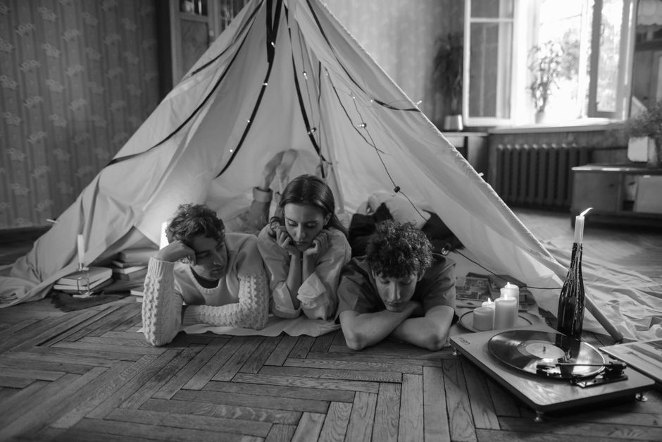 A cozy indoor scene with friends relaxing in a tent, enjoying vinyl music.