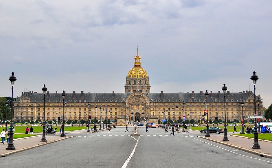 View of the iconic Les Invalides with its golden dome under a cloudy Paris sky.