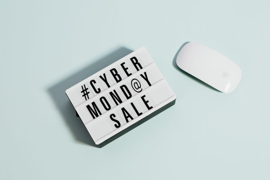 Lightbox sign displaying 'Cyber Monday Sale' beside a computer mouse on a pastel background.