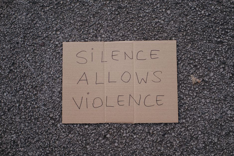 Top view of slogan silence allows violence on carton placed on rough asphalt road on street