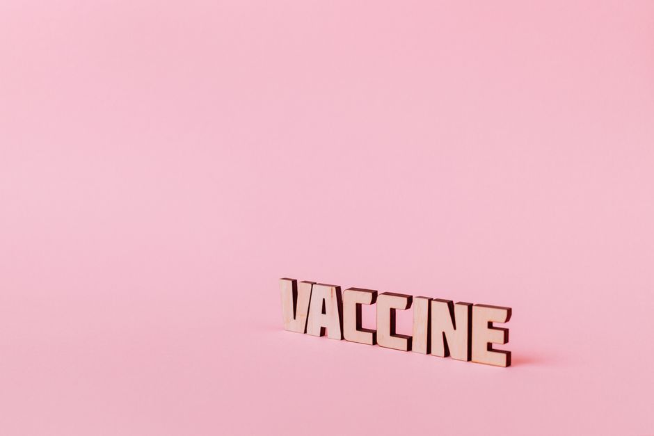 Vaccine lettering on soft pink background, highlighting healthcare concepts.