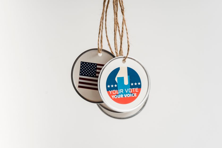 Close-up view of USA voting badges hanging on strings against a white background.