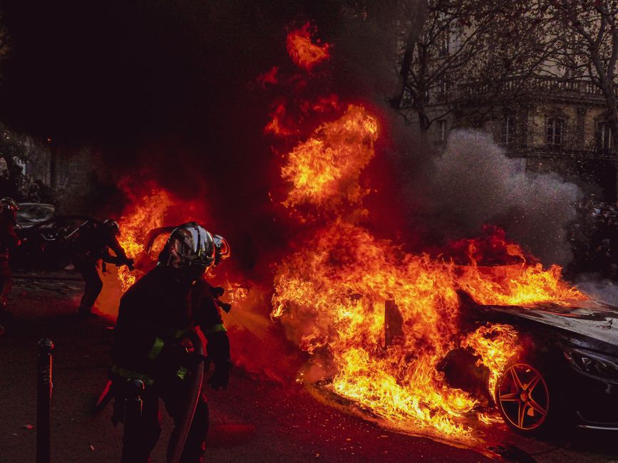 Dramatic image of firefighters responding to a blazing car fire in Paris at night.