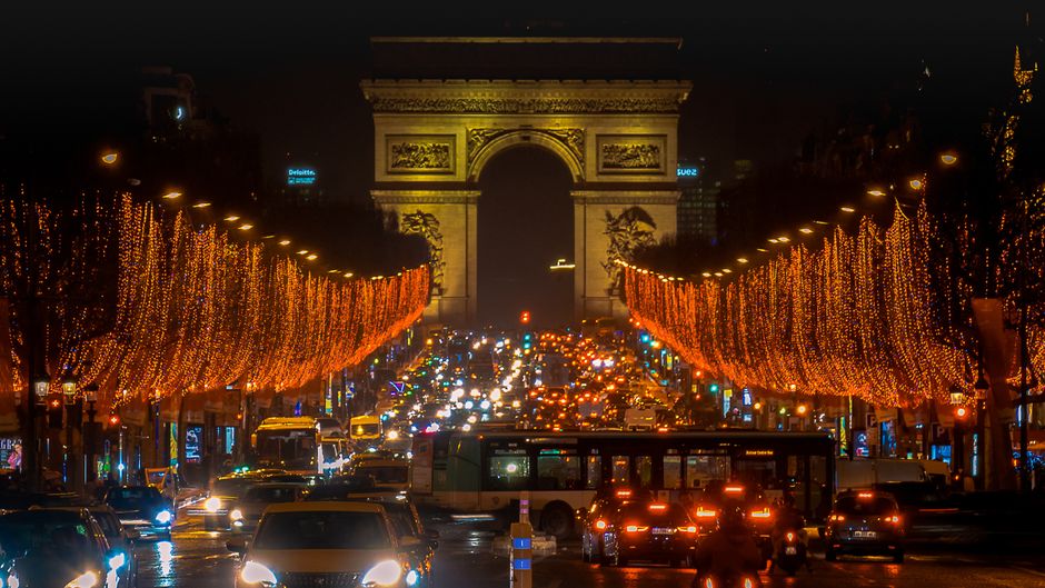 Stunning night view of illuminated Arc de Triomphe and festive Christmas lights on Paris streets.