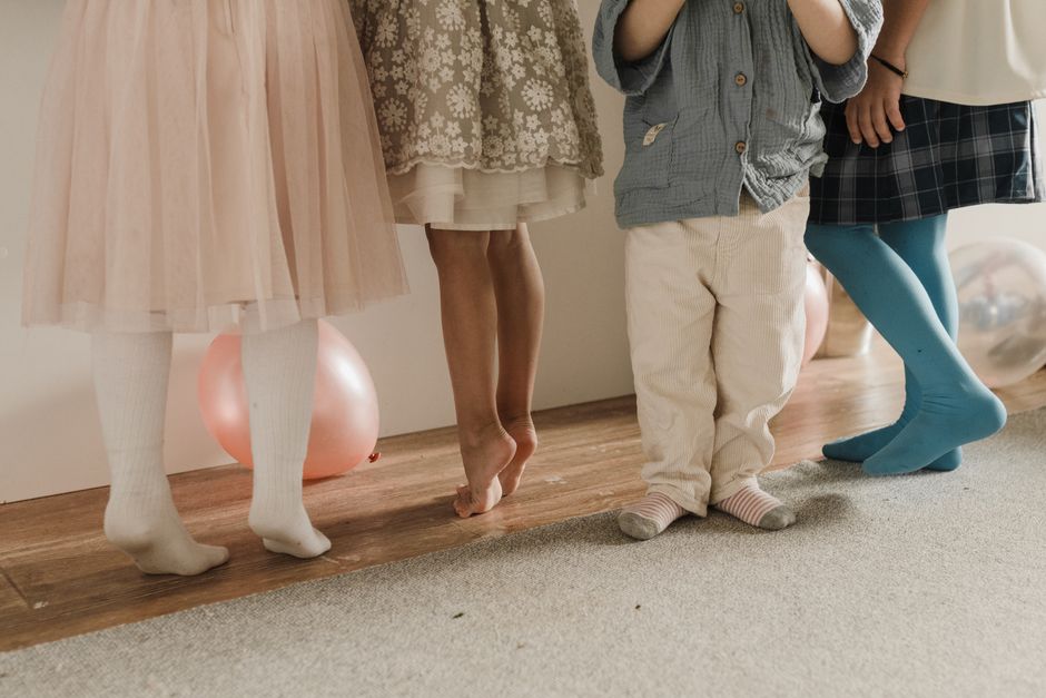 Children's feet and legs at a party with balloons. Joyful scene with kids dancing indoors.