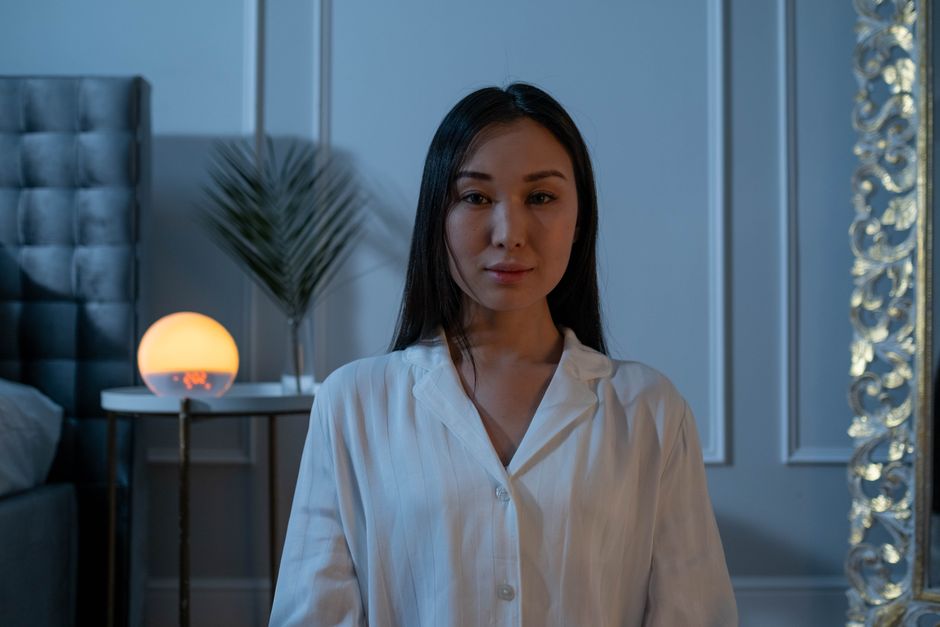 Asian woman in comfortable pajamas with soft lighting, posing indoors at night.