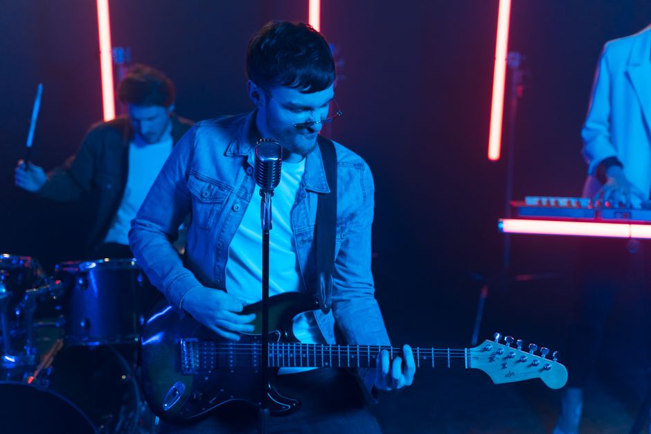 Energetic music performance featuring a guitarist under vibrant neon lights.