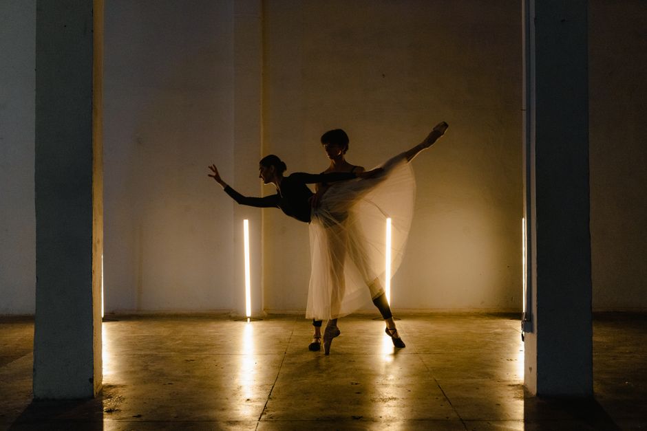 Silhouetted ballet dancers performing gracefully in a dimly lit studio setting.