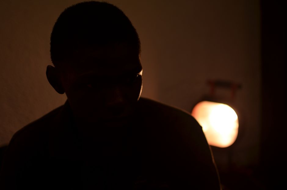 A mysterious silhouette of an adult in warm, dim indoor lighting in Bamako, Mali.