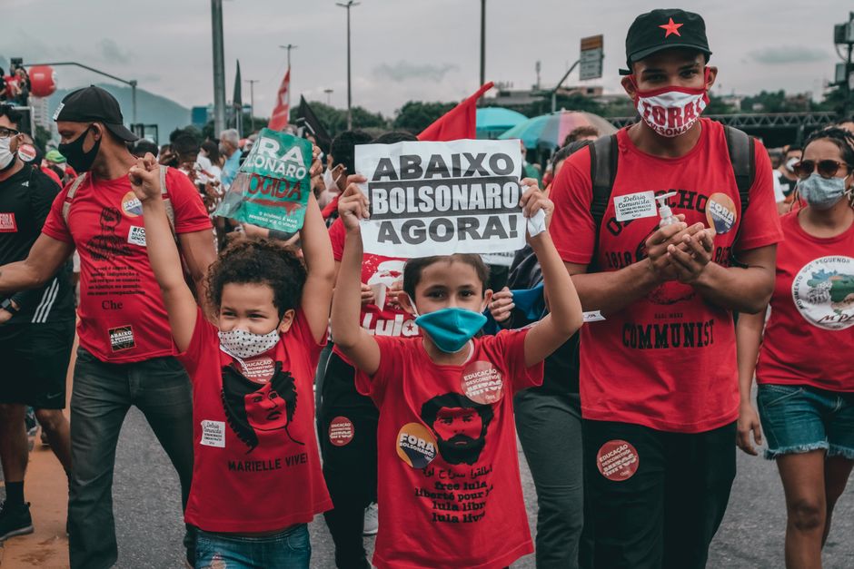 Protesters rallying against Bolsonaro in Rio de Janeiro, showing signs and wearing masks amidst the crowd.