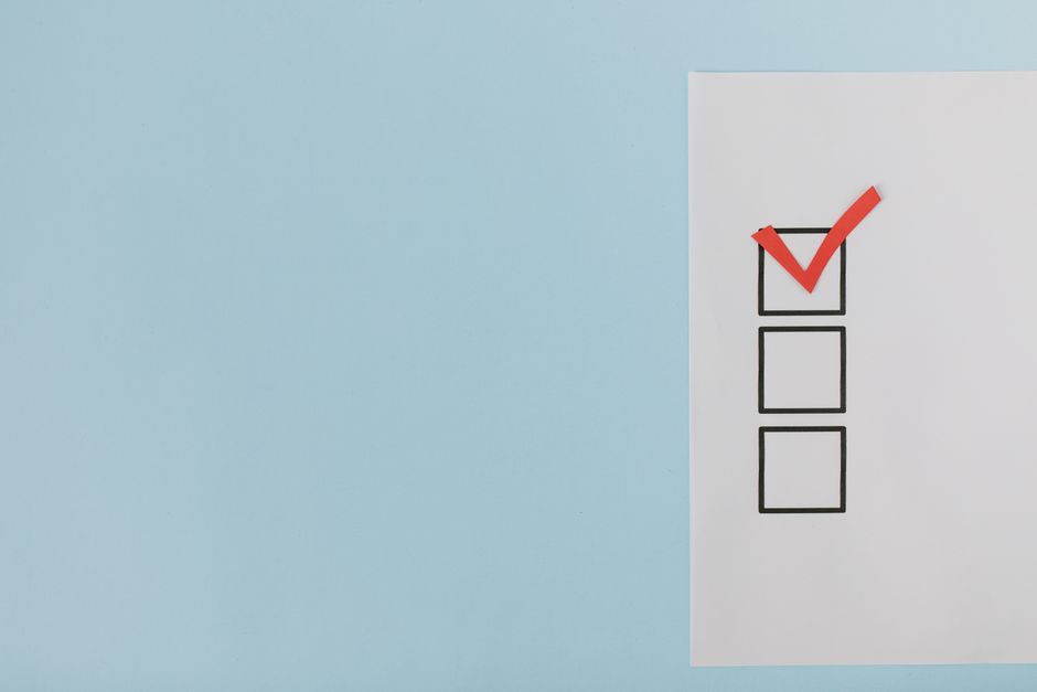A minimalist checklist with a red checkmark on a blue background, providing ample copy space.