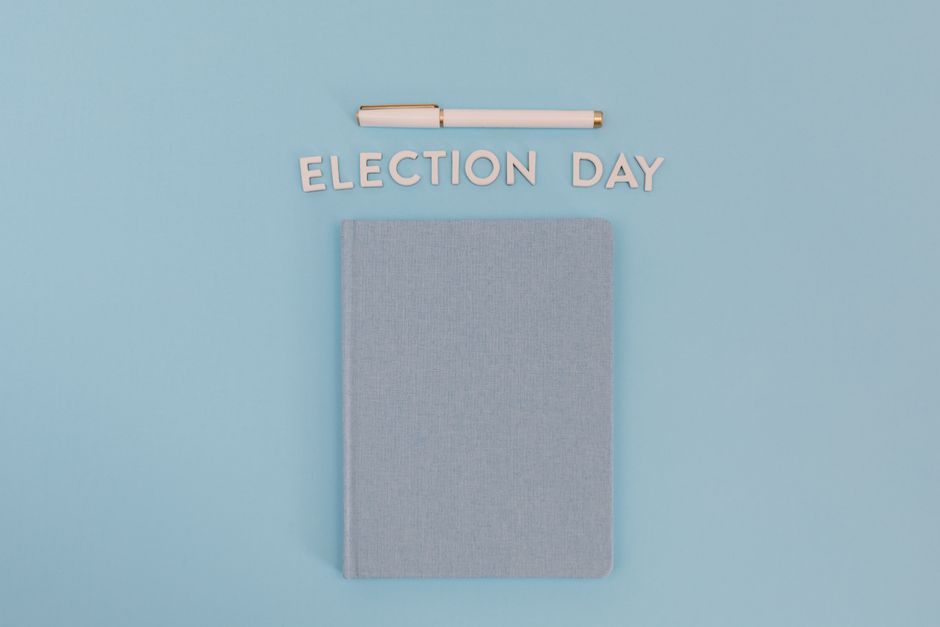 Flat lay of a notebook and pen with 'Election Day' text on a blue background.