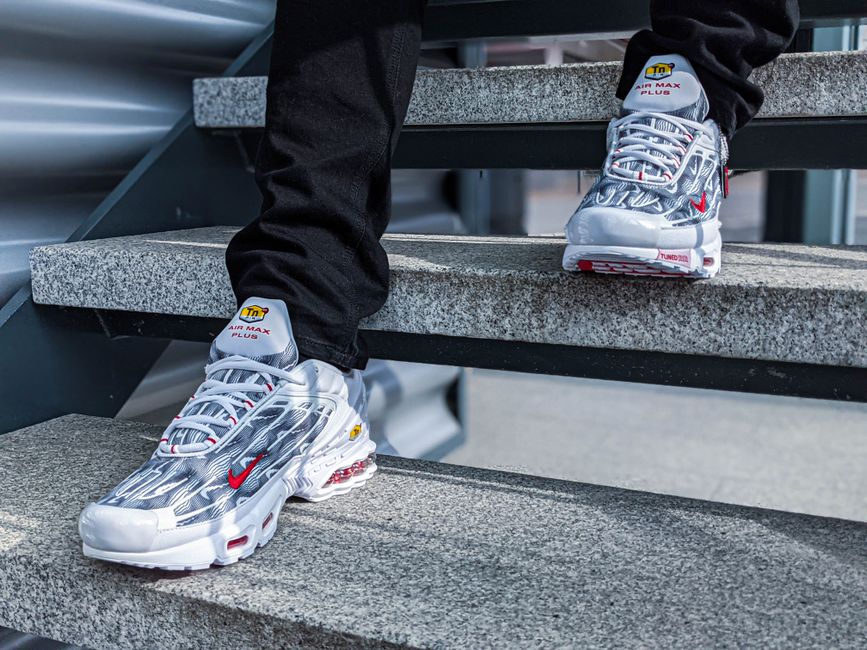 Close-up of sleek Nike Air Max Plus sneakers on outdoor stairs, showcasing modern style.