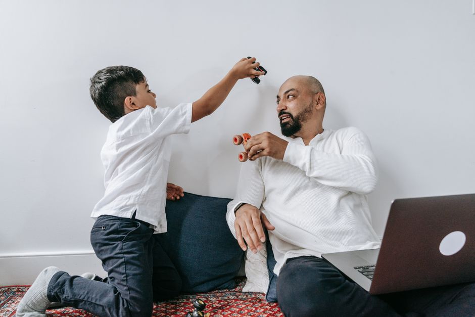 A father and son share a playful moment indoors, enjoying quality bonding time together.