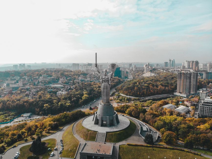 Drone capture of Motherland Monument, featuring Kyiv's cityscape in the background on a clear day